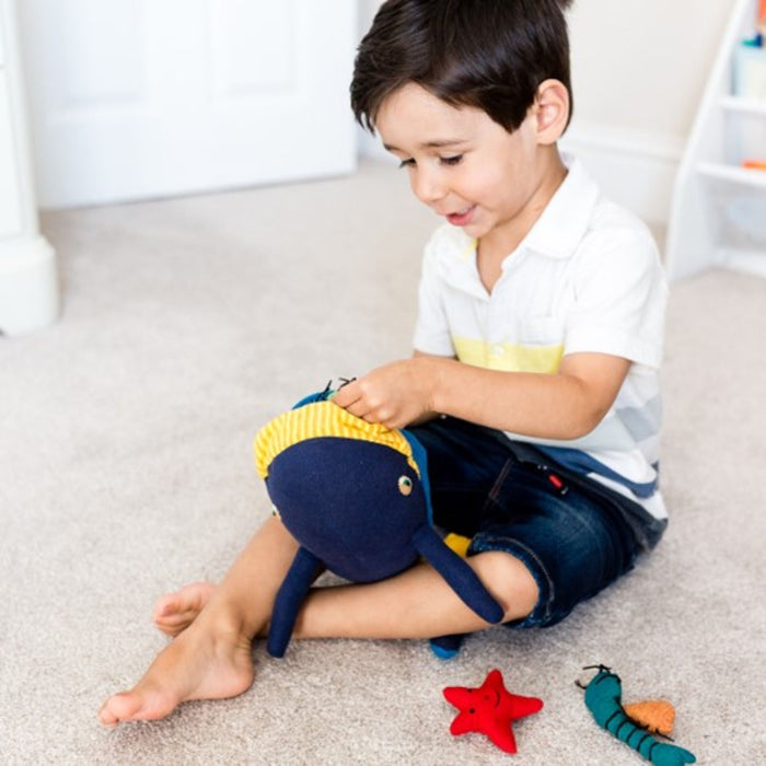 Child playing with the Fair Trade cotton whale and friends soft toy from Weaving Hope